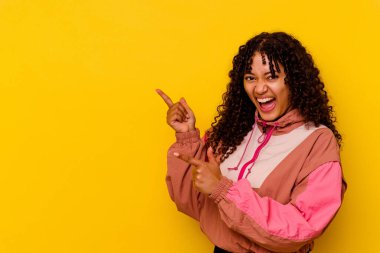 Pembe arka planda izole edilmiş genç melez kadın işaret parmağıyla fotokopi alanını işaret ederek heyecan ve arzusunu ifade ediyor..