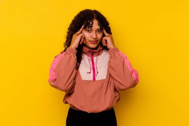 Pembe arka planda izole edilmiş genç melez kadın bir göreve odaklanmış, işaret parmaklarını işaret ediyor..