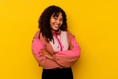 Pembe arka planda soyutlanmış genç melez bir kadın. Kendinden emin, kararlı kollarını kavuşturuyor..