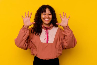 Pembe arka planda izole edilmiş genç melez kadın on numarayı elleriyle gösteriyor..