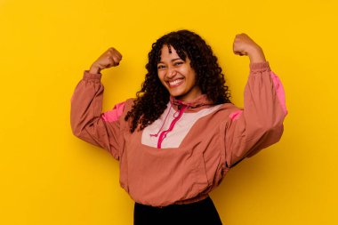 Pembe arka planda soyutlanmış genç melez bir kadın güçlü bir jest yapıyor, kadınsı gücün sembolü.