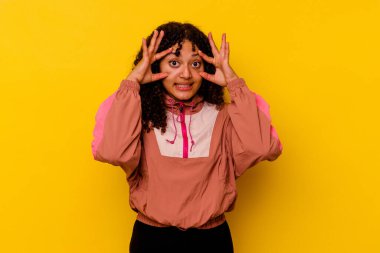 Pembe arka planda izole edilmiş genç melez kadın bir başarı fırsatı bulmak için gözlerini açık tutuyor..