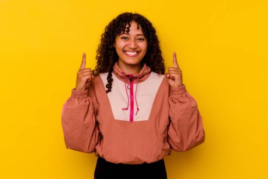 Pembe arka planda izole edilmiş genç melez kadın iki parmağı da boş bir alan gösteriyor..