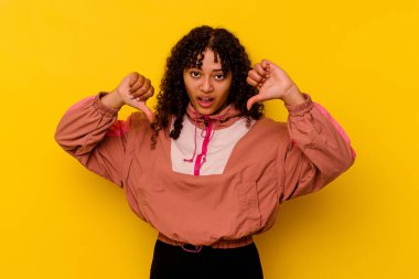 Pembe arka planda izole edilmiş genç melez kadın baş parmağını aşağı gösteriyor ve hoşlanmadığını ifade ediyor..