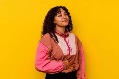 Pembe arka planda soyutlanmış genç melez kadın karnına dokunuyor, nazikçe gülümsüyor, yemek yiyor ve tatmin oluyor..