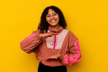 Pembe arka planda izole edilmiş genç bir ırk kadını iki eliyle bir şey tutuyor, ürün sunumu..