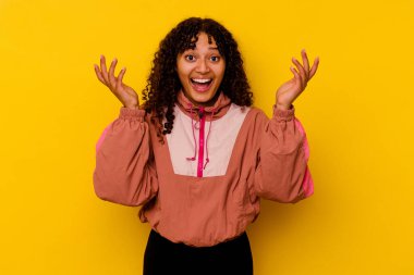 Pembe arka planda soyutlanmış genç melez bir kadın hoş bir sürprizle karşılaşıyor, heyecanlı ve el kaldırıyor..