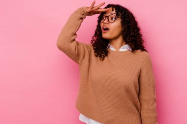 Pembe arka planda soyutlanmış genç bir ırk kadını uzaklara bakıyor ve elini alnına koyuyor..