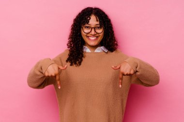 Pembe arka planda izole edilmiş genç melez kadın parmakları aşağıda, pozitif bir his..