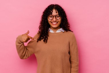 Pembe arka planda izole edilmiş genç bir ırk kadını gömlek fotokopisini elle gösteriyor, gururlu ve kendinden emin.