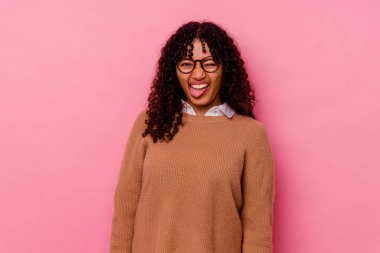 Genç melez kadın pembe arka planda izole edilmiş komik ve dost canlısı bir dil uzatıyor..