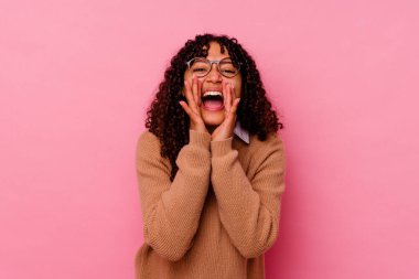 Pembe arka planda soyutlanmış genç melez bir kadın heyecanlı bir şekilde bağırıyor..