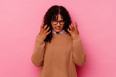 Pembe arka planda izole edilmiş genç melez kadın gergin ellerle çığlık atıyor..