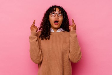 Pembe arka planda izole edilmiş, ağzı açık, üst tarafı gösteren genç melez bir kadın..