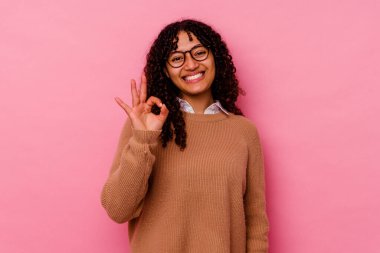 Genç melez kadın pembe arka planda izole edilmiş neşeli ve kendinden emin, iyi bir hareket gösteriyor..