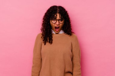 Pembe arka planda izole edilmiş genç melez kadın çok sinirli ve agresif bağırıyor..