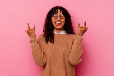 Pembe arka planda izole edilmiş genç melez kadın parmaklarıyla taş hareketi gösteriyor.