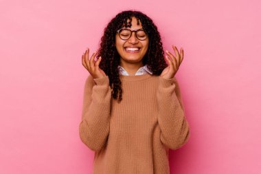 Genç melez kadın pembe arka planda izole edilmiş neşeli bir şekilde gülüyor. Mutluluk kavramı.