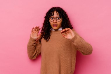 Pembe arka planda izole edilmiş genç melez bir kadın yaklaşan bir tehlike nedeniyle şok oluyor.