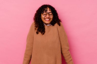 Pembe arka planda soyutlanmış genç melez kadın gülüyor ve gözlerini kapıyor, rahatlamış ve mutlu hissediyor..