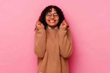 Genç melez kadın pembe arka planda izole edilmiş mutlu ve başarılı hissediyor. Zafer konsepti.