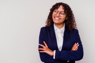 Genç iş kadını, beyaz arka planda soyutlanmış kollarını kavuşturarak gülümsüyor..