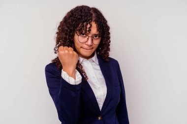 Beyaz arka planda izole edilmiş genç iş kadını kameraya yumruk gösteriyor, agresif yüz ifadesi var..