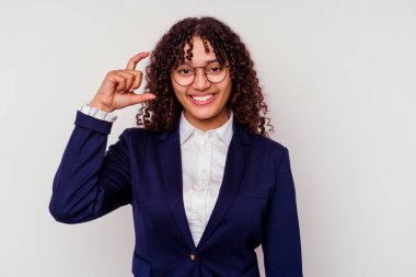 Beyaz arka planda izole edilmiş genç bir iş kadını. Elinde küçük bir işaret parmağı olan, gülümseyen ve kendinden emin bir şey tutuyor..