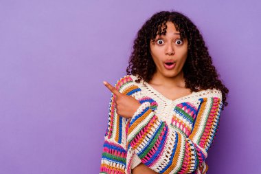 Mor arka planda izole edilmiş genç melez kadın yan tarafı gösteriyor.