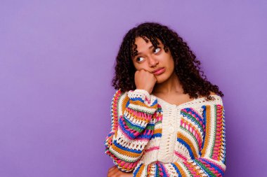 Mor arka planda soyutlanmış, üzgün ve dalgın hisseden, kopyalama alanına bakan genç melez bir kadın..