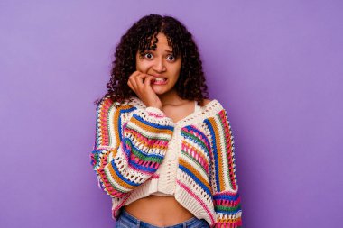 Mor arka planda izole edilmiş, tırnak yiyen, gergin ve endişeli genç bir ırk kadını..