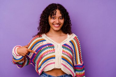 Mor arka planda izole edilmiş genç bir ırk kadını gömlek fotokopisini elle gösteriyor, gururlu ve kendinden emin.