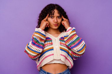 Mor arka planda izole edilmiş genç melez kadın bir göreve odaklanmış, işaret parmaklarını işaret ediyor..