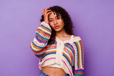 Mor arka planda soyutlanmış genç bir ırk kadını yorgun ve uykulu bir şekilde ellerini başının üstünde tutuyor..