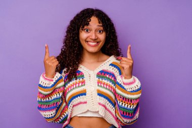 Mor arka planda izole edilmiş genç melez kadın iki parmağı da boş bir alan gösteriyor..
