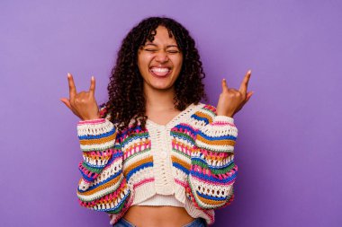 Mor arka planda izole edilmiş genç melez kadın parmaklarıyla taş hareketi gösteriyor.