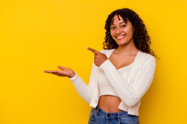 Sarı arka planda izole edilmiş genç melez bir kadın. Elinde bir kopyası olduğu için heyecanlı..