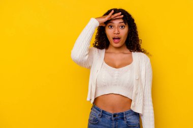 Sarı arka planda soyutlanmış genç melez kadın yüksek sesle bağırıyor, gözleri açık ve elleri gergin tutuyor..