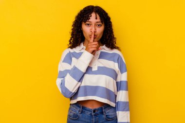 Sarı arka planda izole edilmiş genç melez bir kadın ya sır saklıyor ya da sessizlik istiyor..