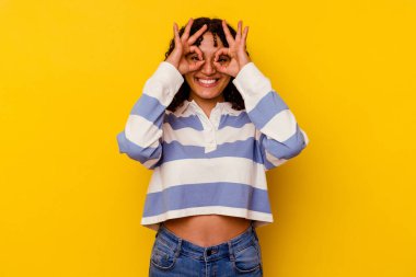 Sarı arka planda izole edilmiş genç melez kadın gözlerde sorun olmadığını gösteriyor.