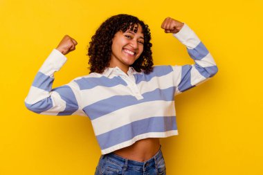 Sarı arka planda soyutlanmış genç melez bir kadın özel bir günü kutluyor, kollarını enerji ile kaldırıyor ve zıplıyor..