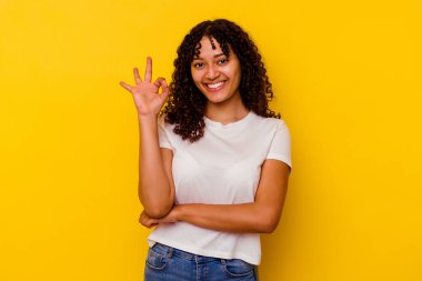 Sarı arka planda izole edilmiş genç bir ırk kadını göz açıp kapayıncaya kadar elinde iyi bir el hareketi tutuyor..