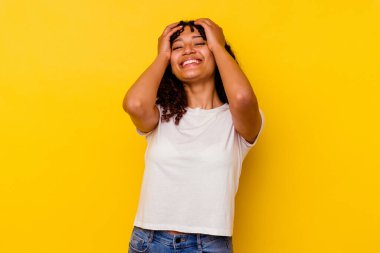 Sarı arka planda soyutlanmış melez bir kadın ellerini başının üstünde tutarak neşeyle gülüyor. Mutluluk kavramı.