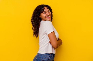 Sarı arka planda izole edilmiş genç melez kadın mutlu, güler yüzlü ve neşeli..