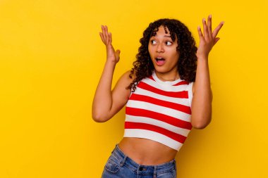 Sarı arka planda izole edilmiş genç bir ırk kadını gökyüzüne haykırıyor, yukarı bakıyor ve hayal kırıklığına uğruyor..