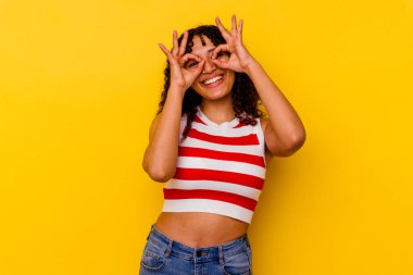 Sarı arka planda izole edilmiş genç melez kadın gözlerde sorun olmadığını gösteriyor.