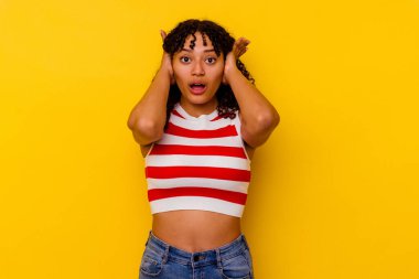 Sarı arka planda izole edilmiş genç bir ırk kadını. Kulaklarını ellerle kapatıyor. Çok yüksek ses duymamaya çalışıyor..
