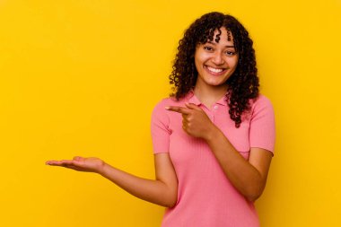 Sarı arka planda izole edilmiş genç melez bir kadın. Elinde bir kopyası olduğu için heyecanlı..