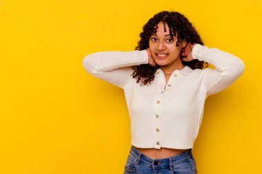 Genç melez kadın sarı arka planda izole edilmiş kafasının arkasına dokunuyor, düşünüyor ve bir seçim yapıyor..