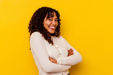 Sarı arka planda izole edilmiş genç melez bir kadın. Komik ve dost canlısı bir dil uzatıyor..